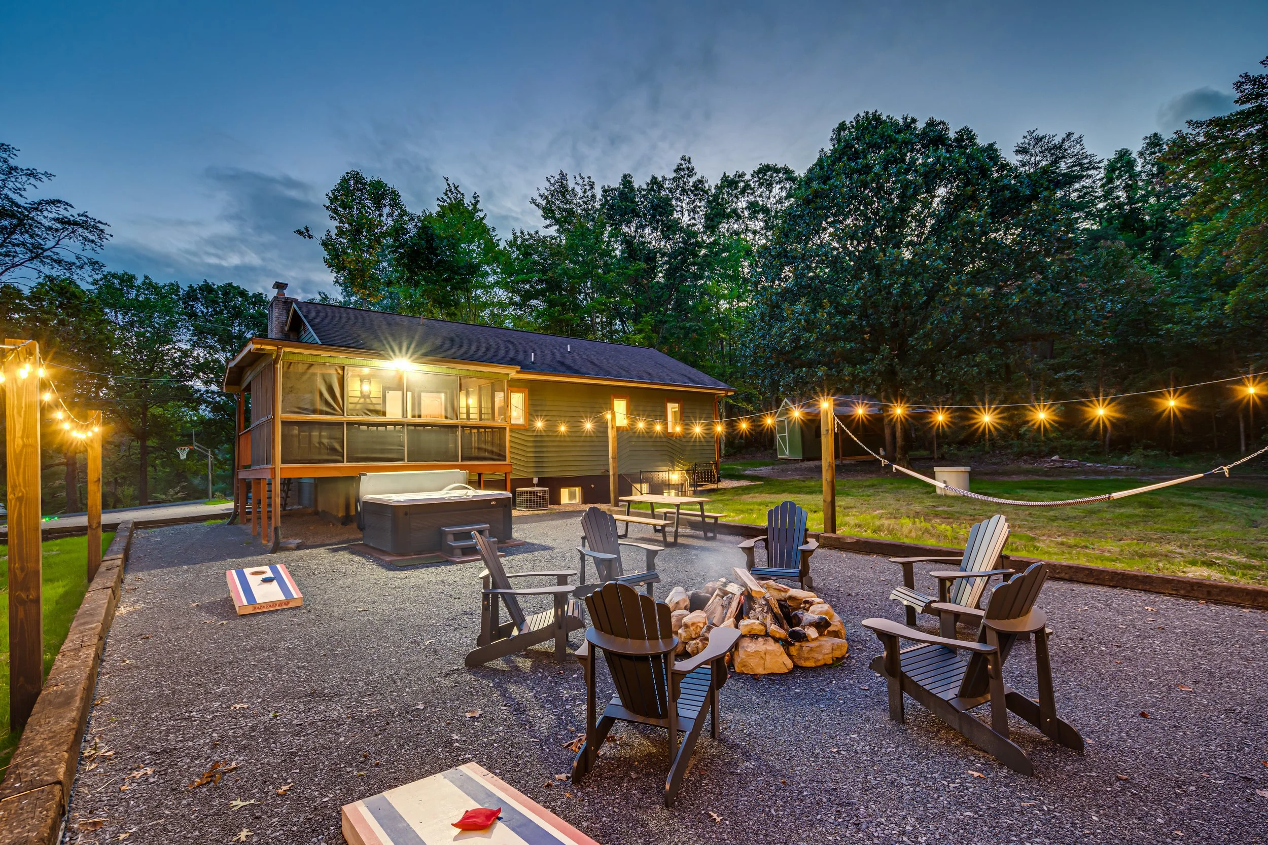 Luray Oasis cabin at twilight with fire pit, hot tub, hammock and string lights